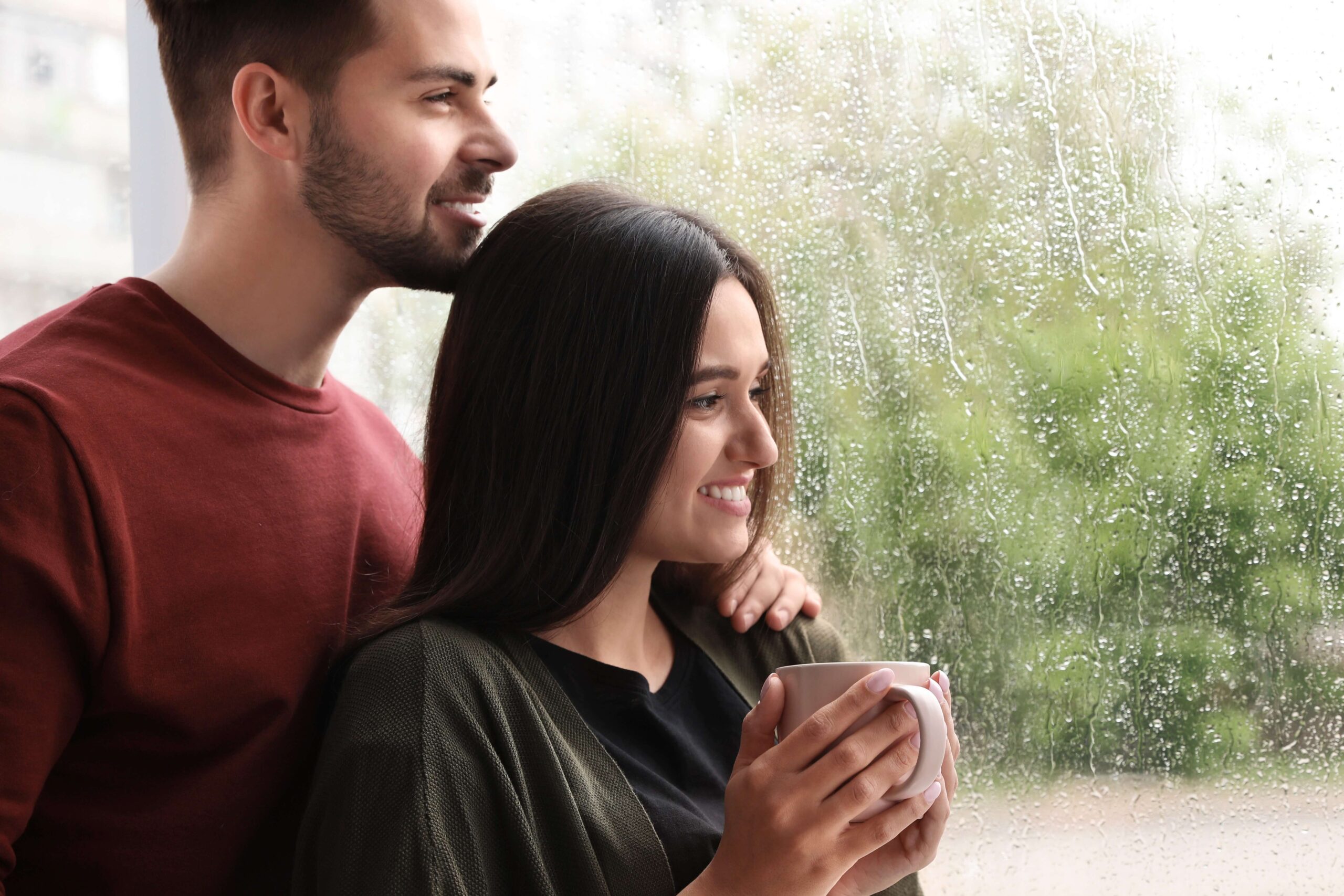 A man and a woman looking out of a window as it is Raining In Georgia.